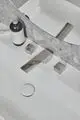 Waschtisch mit einer dreilochigen Armatur von Ideal Standard. Chromoberfläche, zwei Steuerknöpfe und ein Wassertropfenabfluss in einem minimalistischen Design.